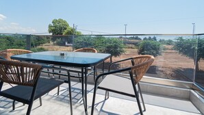 A terrace with a table and chairs, overlooking a vineyard. - Ireon Luxury Suites 4 by RentalsPro - Nea Plagia Halkidiki (Nea Plagia)