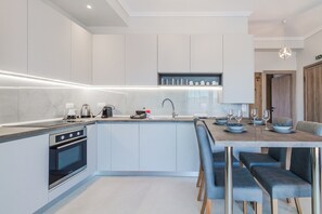 Eine moderne Küche mit Einbauofen, Spüle und Essbereich mit Tisch für zwei Personen.