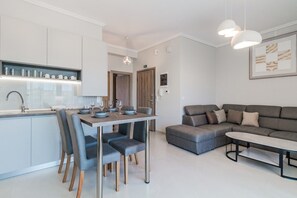 Eine moderne Küche mit Essbereich, einem grauen Sofa und Pendelleuchten.