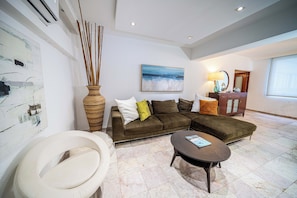 Ein modernes Wohnzimmer mit einem Ecksofa, einem runden Couchtisch und einem großen Gemälde an der Wand.