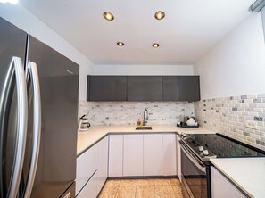 A modern kitchen with white cabinets, a stainless steel refrigerator, a tiled backsplash, and a built-in oven. - 3-bedroom apartment in the best location in Condado (San Juan)