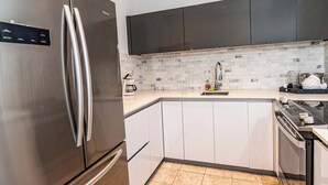 Uma cozinha moderna com eletrodomésticos de aço inoxidável, armários brancos e painel de azulejos.