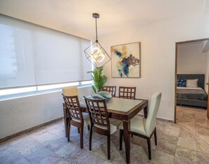 Ein Essbereich mit Tisch, Stühlen, einer Pendelleuchte, einem Blumentopf und einem Bild an der Wand.