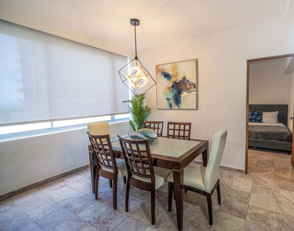A dining area with a table, chairs, a hanging light fixture, a potted plant, and a painting on the wall. - 3-bedroom apartment in the best location in Condado (San Juan)