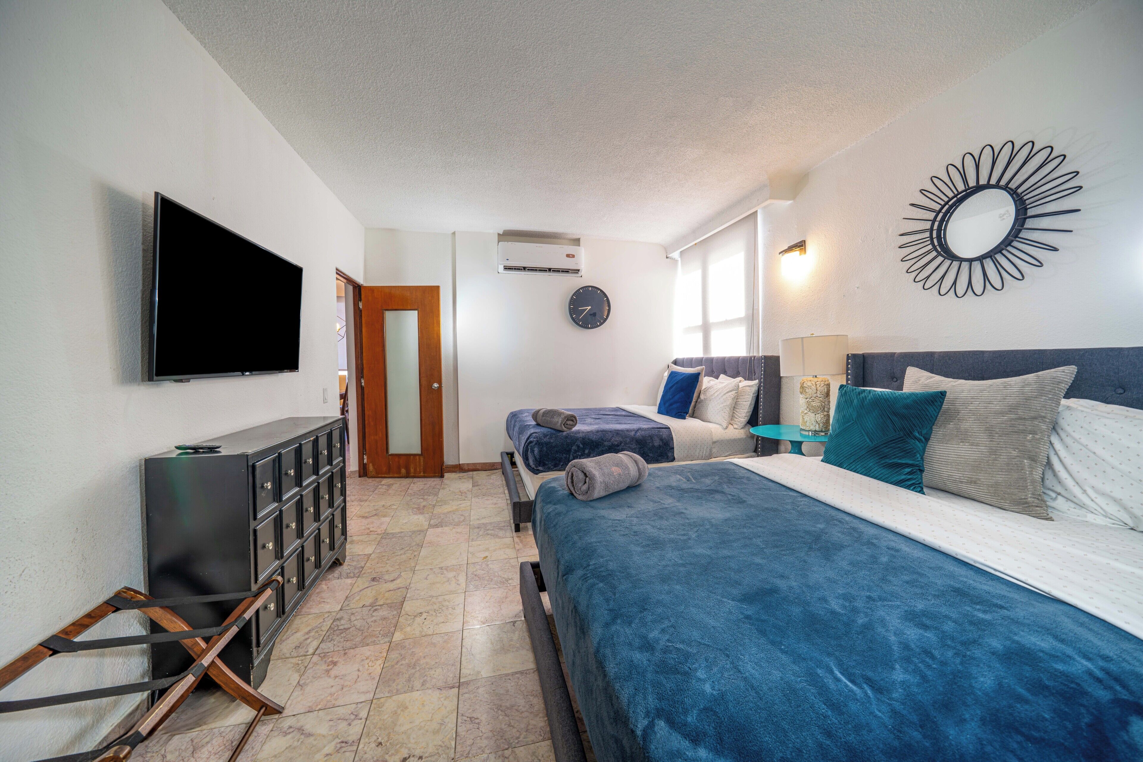 A hotel room with a large bed, a TV, a wardrobe, and a mirror on the wall.