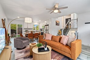 Ein modernes Wohnzimmer mit einer Couch, einem Couchtisch und einem Essbereich mit Stühlen.