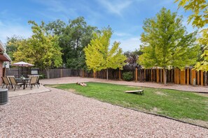 Ein Garten mit Terrasse, Grill und Holzzaun.