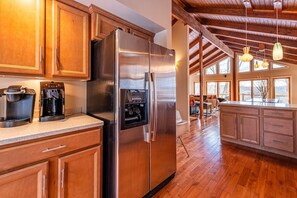 Eine Küche mit Holzschränken, einem Edelstahl-Kühlschrank, einer Kaffeemaschine und einem integrierten Eisbereiter.