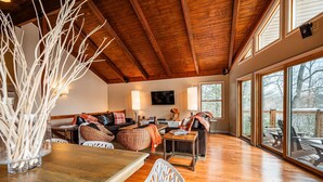 Un salón amplio con techo de madera, un ventanal grande y una chimenea.