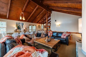 A cozy living room with a wooden ceiling, a sofa set, a dining table, and a kitchen area. - Luxury home on The Meadow River with stunning view of the river canyon (Hico)