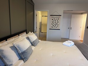 A bedroom with a bed, pillows, a hanging wall decoration, and a door leading to another room. - Charming 4BR Lakefront Condo Getaway- Near Boat Marina and Silver Dollar City. (Branson)