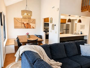 Ein modernes Wohnzimmer mit einem dunklen Sofa, einem Holzessttisch und einer Chandelier.