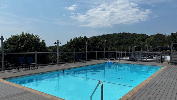 A rectangular swimming pool with a wooden deck surrounding it, equipped with a ladder and safety ropes. - Charming 4BR Lakefront Condo Getaway- Near Boat Marina and Silver Dollar City. (Branson)