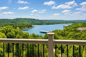 A scenic view of a lake surrounded by lush greenery, with a dock and a house visible in the foreground. - Charming 4BR Lakefront Condo Getaway- Near Boat Marina and Silver Dollar City. (Branson)