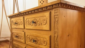 Eine Holzkommode mit geschnitzten Details, ein kleiner Block darauf und ein Holzboden.