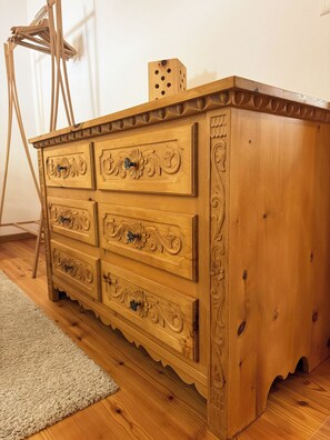 Eine Holzkommode mit geschnitzten Details, ein kleiner Block darauf und ein Holzboden.