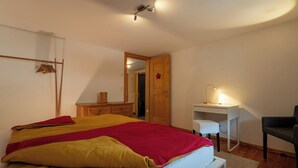Ein Schlafzimmer mit Bett, Schreibtisch, Stuhl und einer Tür zu einem anderen Raum.