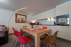 Eine moderne Küche mit weißen Schränken, einem Holztisch und roten Stühlen.
