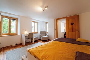 Ein Schlafzimmer mit Bett, Schreibtisch, Stuhl und einer Tür mit Herzdeko.