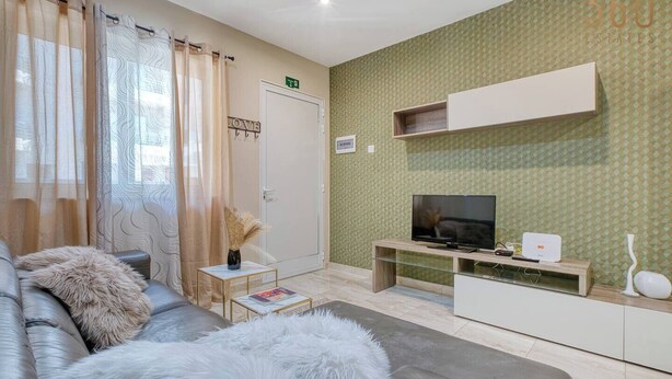 Un salon moderne avec un canapé, un téléviseur et une petite table.