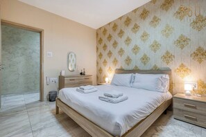 A hotel room with a bed, bedside tables, a mirror, and a patterned wallpaper. - 3BR home with private large terrace in Marsascala (Marsaskala)