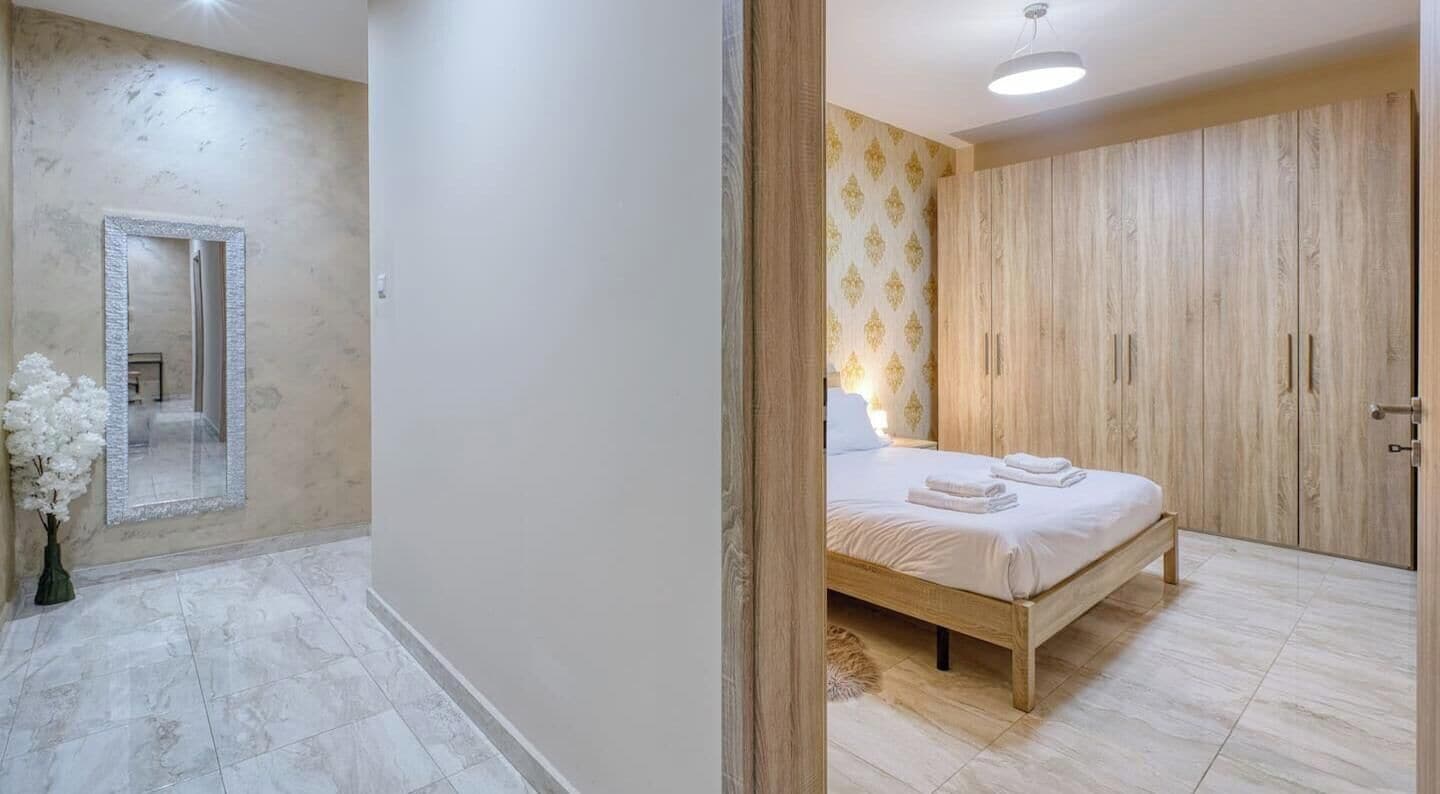 Quarto com uma cama, guarda-roupa e espelho.
