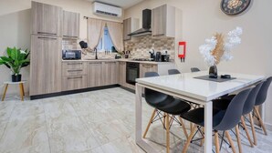Une cuisine moderne avec un coin repas, comprenant une table blanche, des chaises noires et une plante en pot.