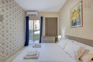 Una habitació d'hotel amb un llit, una taula de nit, una làmpada, un quadre i vista a l'exterior.