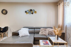 A modern living room with a leather sofa, a white fluffy throw, and a decorative wall piece. - 3BR home with private large terrace in Marsascala (Marsaskala)