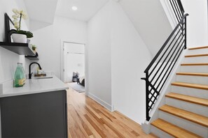 Un intérieur moderne comprenant un espace cuisine, un escalier et un couloir menant à une chambre.
