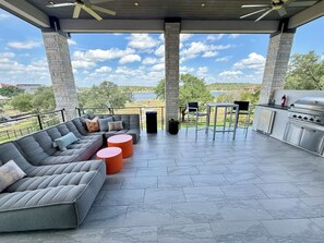 Eine Terrasse im Freien mit Kamin aus Stein, einer Sitzecke und Grillplatz.