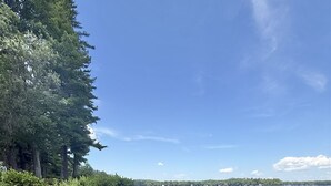 Ein Strand mit klarem Wasser, sandigem Ufer und dichter Bäuraum im Hintergrund.