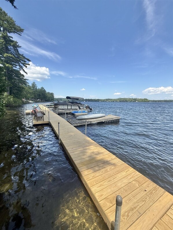 A wooden dock extending into a calm lake with boats docked at the end.