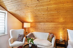 A cozy room with a sloped ceiling, two armchairs with patterned cushions, a small table with a potted plant, and a floor lamp. - Studio-Apartment 'Lena Apartments 3' (Bischofshofen)