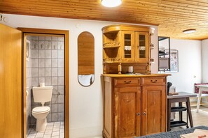 Un baño con inodoro, un armario de madera y un espejo.