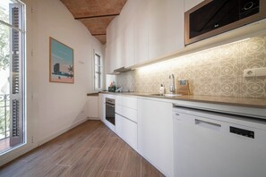 A modern kitchen with white cabinetry, a stainless steel range hood, and a patterned backsplash. - 3 Bedroom Apartment Uptown Barcelona (Barcelona)