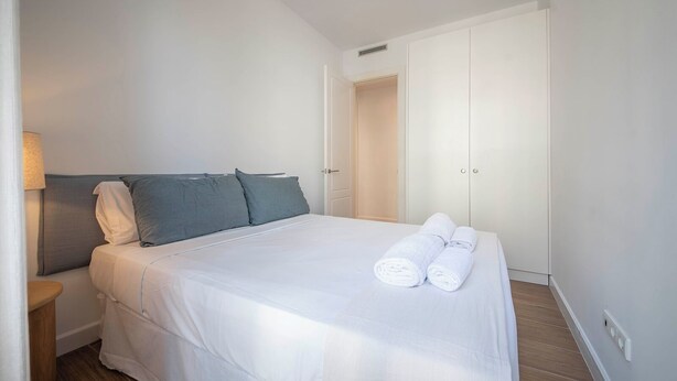 Ein Hotelzimmer mit einem Bett, einem Nachttisch, einer Lampe, einem Kleiderschrank und einem Paar Handtüchern.