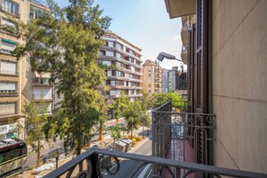 A residential building with multiple balconies, a street view with trees, and a clear sky. - 3 Bedroom Apartment Uptown Barcelona (Barcelona)