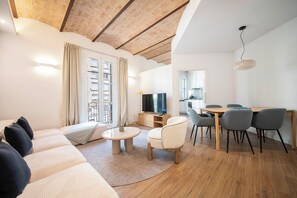 A modern living room with a sofa, a coffee table, and a dining area with chairs and a table. - 3 Bedroom Apartment Uptown Barcelona (Barcelona)