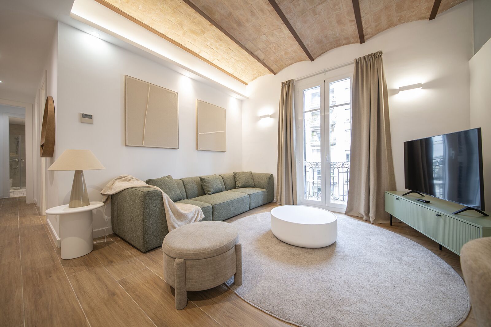 Ein modernes Wohnzimmer mit einer Couch, einem Hocker und einem Flachbildfernseher.