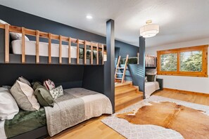 A modern bedroom with a built-in bench, a staircase, a large window, and a cowhide rug. - The Grand Après | Hot Tub | Gym+Sauna & Theater (Park City)