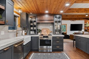 A modern kitchen with dark cabinetry, stainless steel appliances, and a wooden ceiling. - The Grand Après | Hot Tub | Gym+Sauna & Theater (Park City)