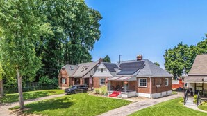 A residential house with a driveway, a lawn, and a large tree. - The Cher e (Cincinnati)