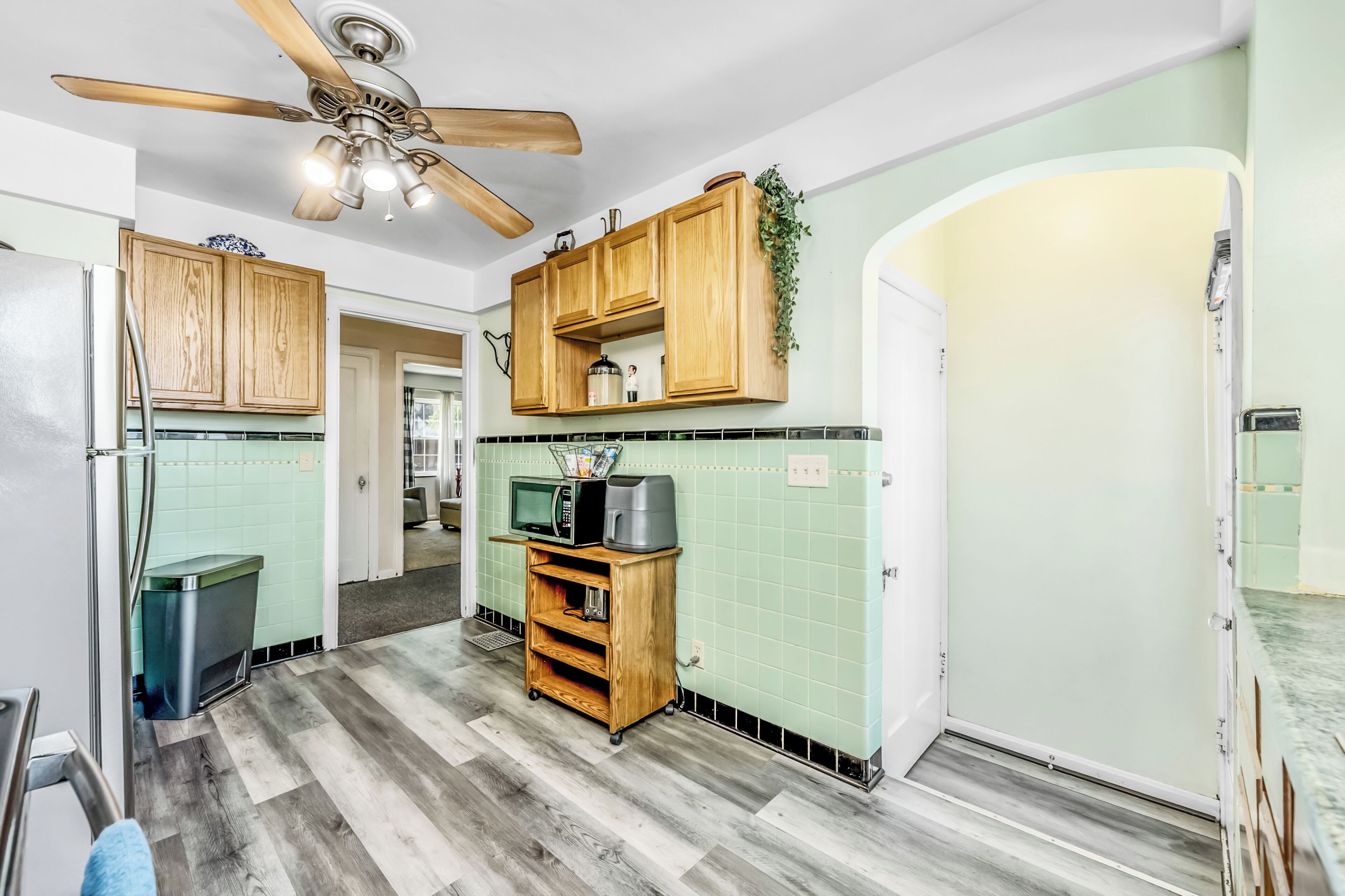 A kitchen with wooden cabinets, a microwave, a coffee maker, and a ceiling fan.