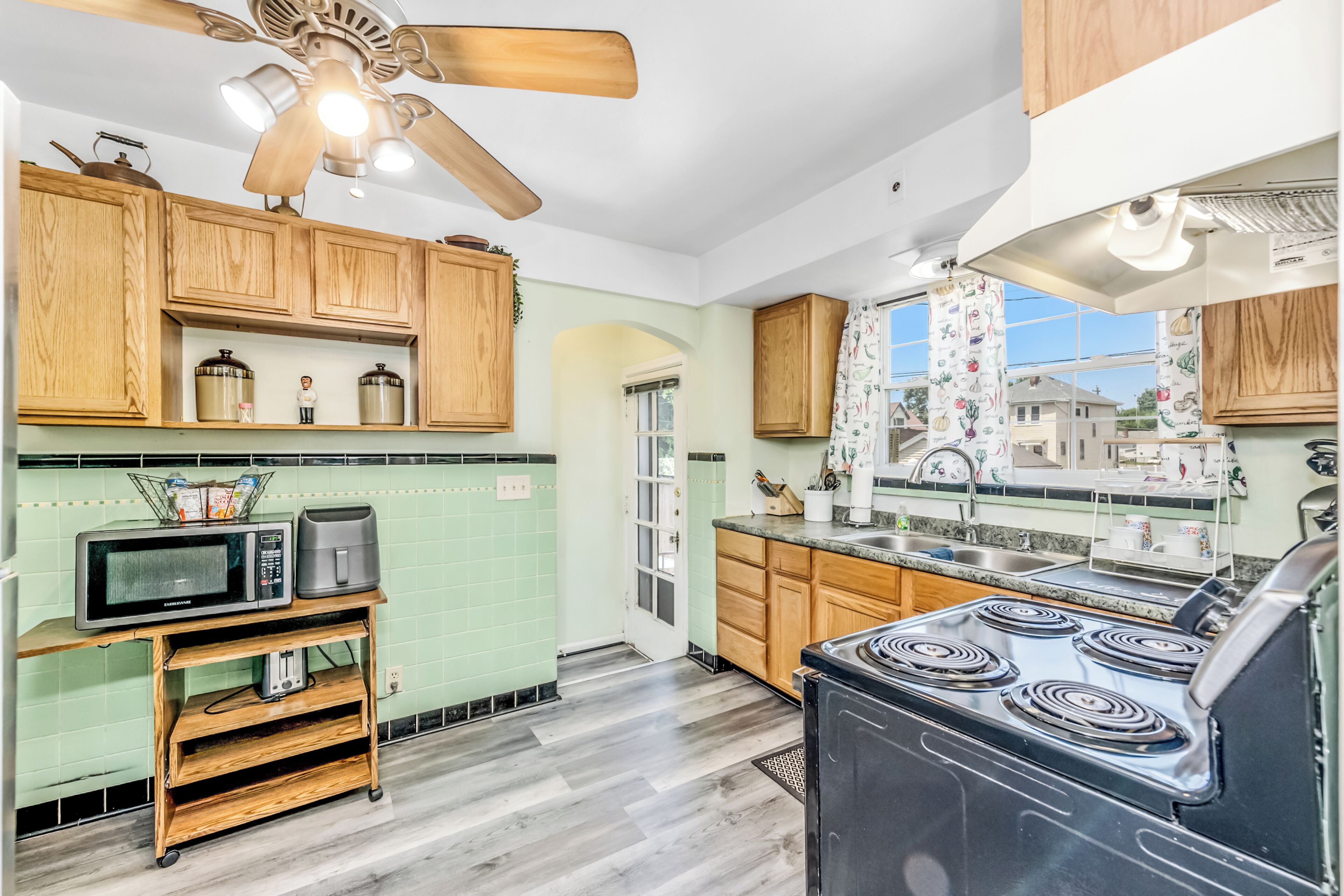 A kitchen with wooden cabinets, a microwave, a stove, and a ceiling fan.