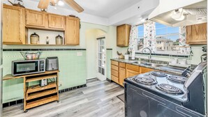 A kitchen with wooden cabinets, a microwave, a stove, and a ceiling fan. - The Cher e (Cincinnati)