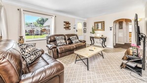 A living room with a brown leather sofa, a wooden coffee table, and a television. - The Cher e (Cincinnati)