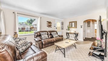 A living room with a brown leather sofa, a wooden coffee table, and a television.