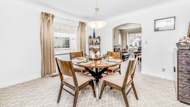 A dining area with a round table, chairs, and a hanging light fixture. - The Cher e (Cincinnati)