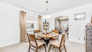 A dining area with a round table, chairs, and a hanging light fixture.